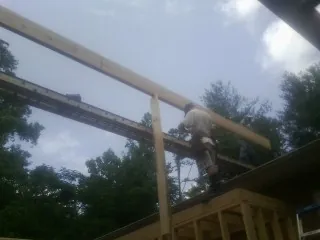 Carpenter setting a ridge beam over a new addition frame — Ice Dam Removal by Roofing Brothers in Kilmarnock