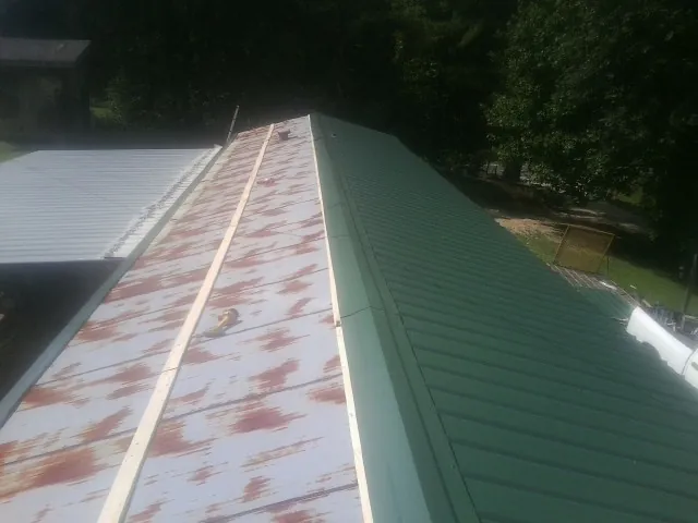 Old rusted panels beside newly installed green metal roofing — Wind Damage Roof Repair by Roofing Brothers in Kilmarnock