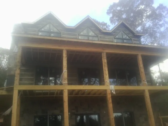 Dormers and porch framing on a large log home under construction — Roof Coating work by our crew in Kilmarnock