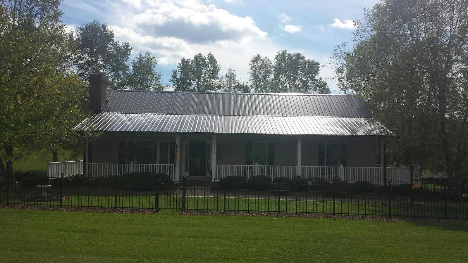 Gray metal roof on a brick ranch with a full width front porch — Gutter Guard Installation work by our crew in Kilmarnock