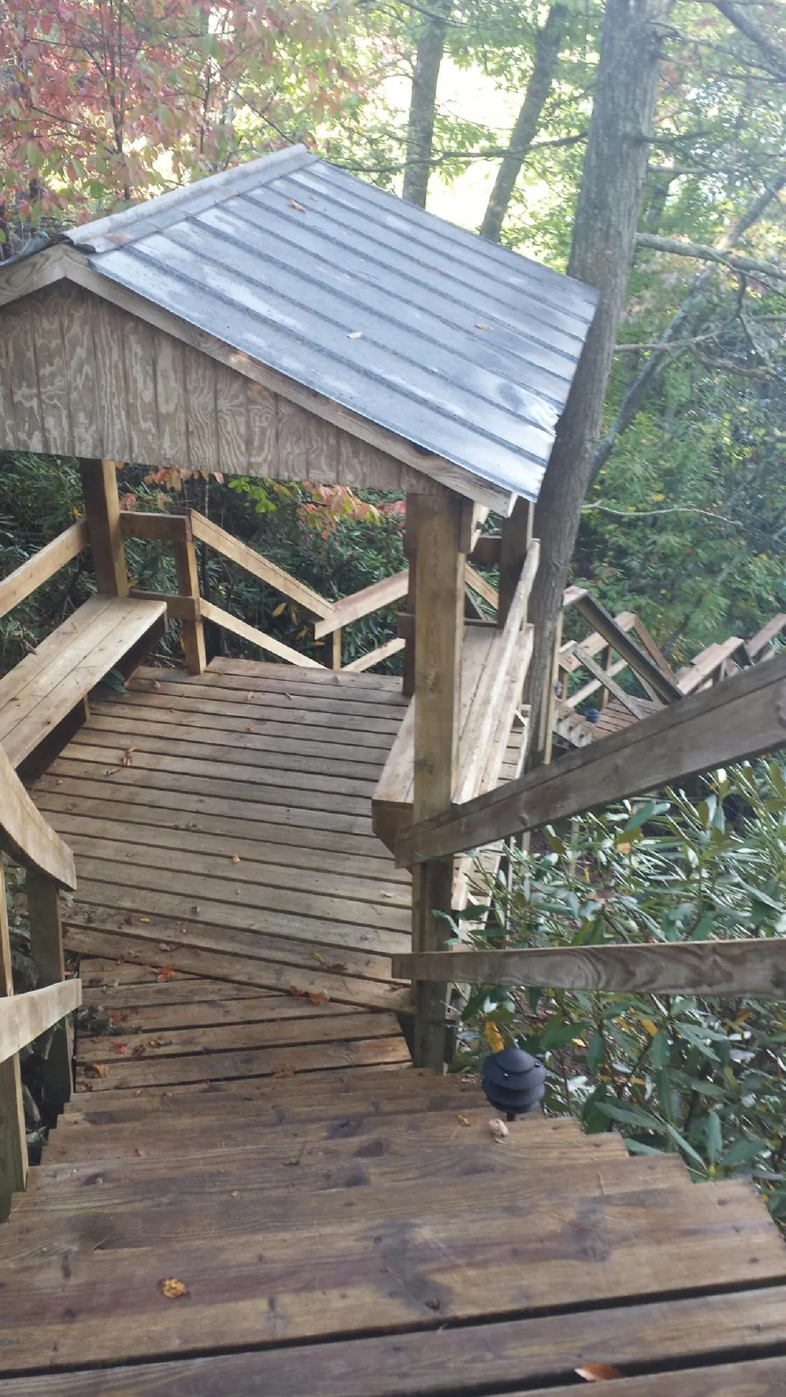 Metal roofed shelter over wooden steps on a wooded walkway — Skylight Repair & Installation work by our crew in Kilmarnock
