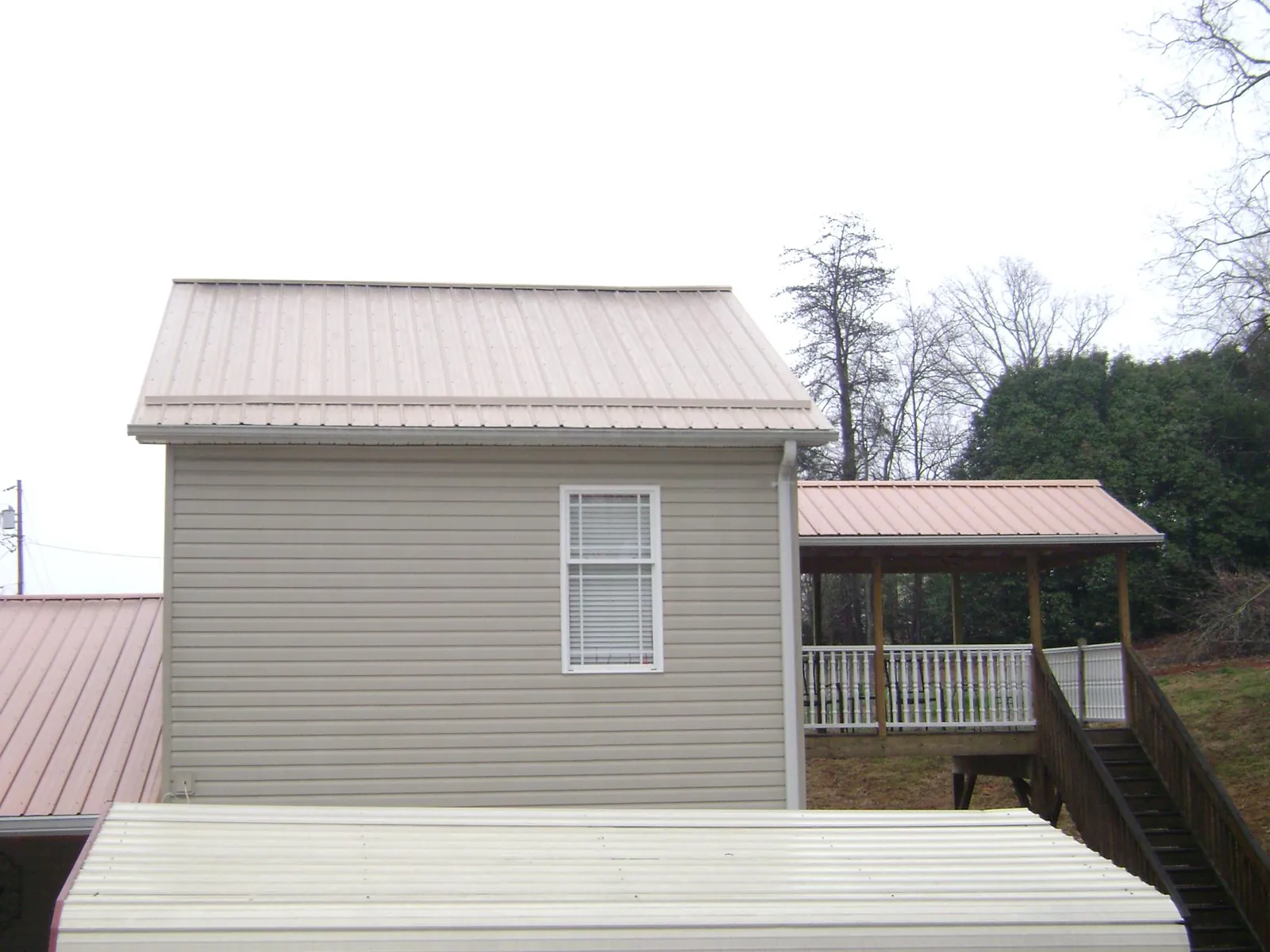 Tan metal roofs on a two story addition and attached porch, from a Roof Replacement job in Kilmarnock