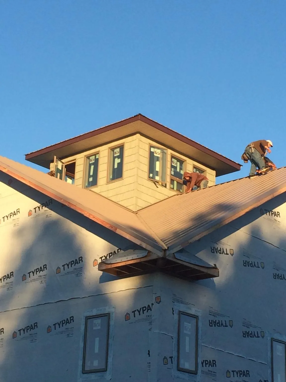 Roofers working around a rooftop cupola on a new metal roof at sunset — Roof Waterproofing in Kilmarnock by Roofing Brothers